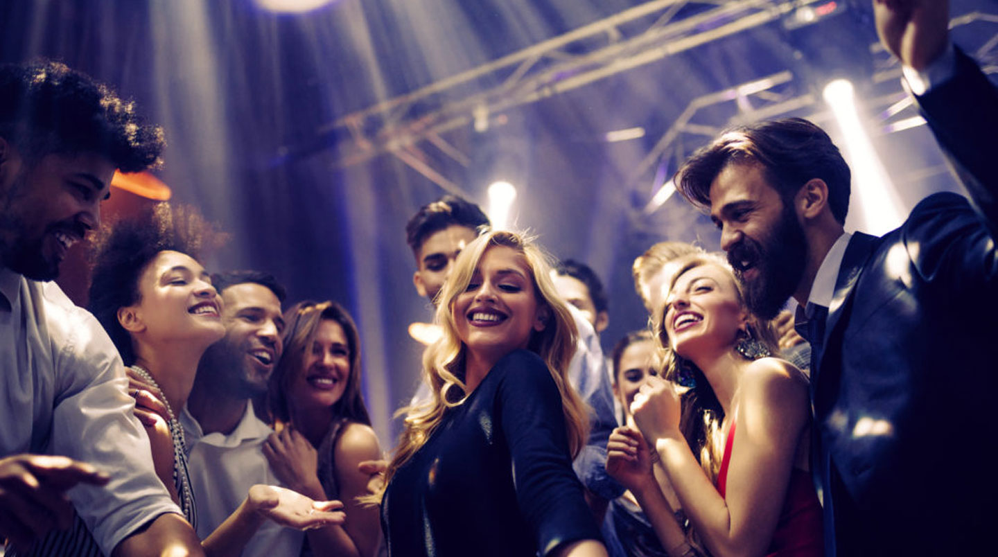 Pre-party in bar all'aperto di Magaluf con gruppo di giovani che socializza con cocktail nelle prime ore della sera