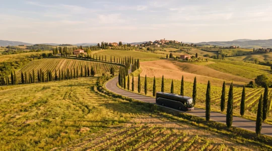 Bus turistico che percorre una strada di campagna attraverso il paesaggio toscano con cipressi e vigneti